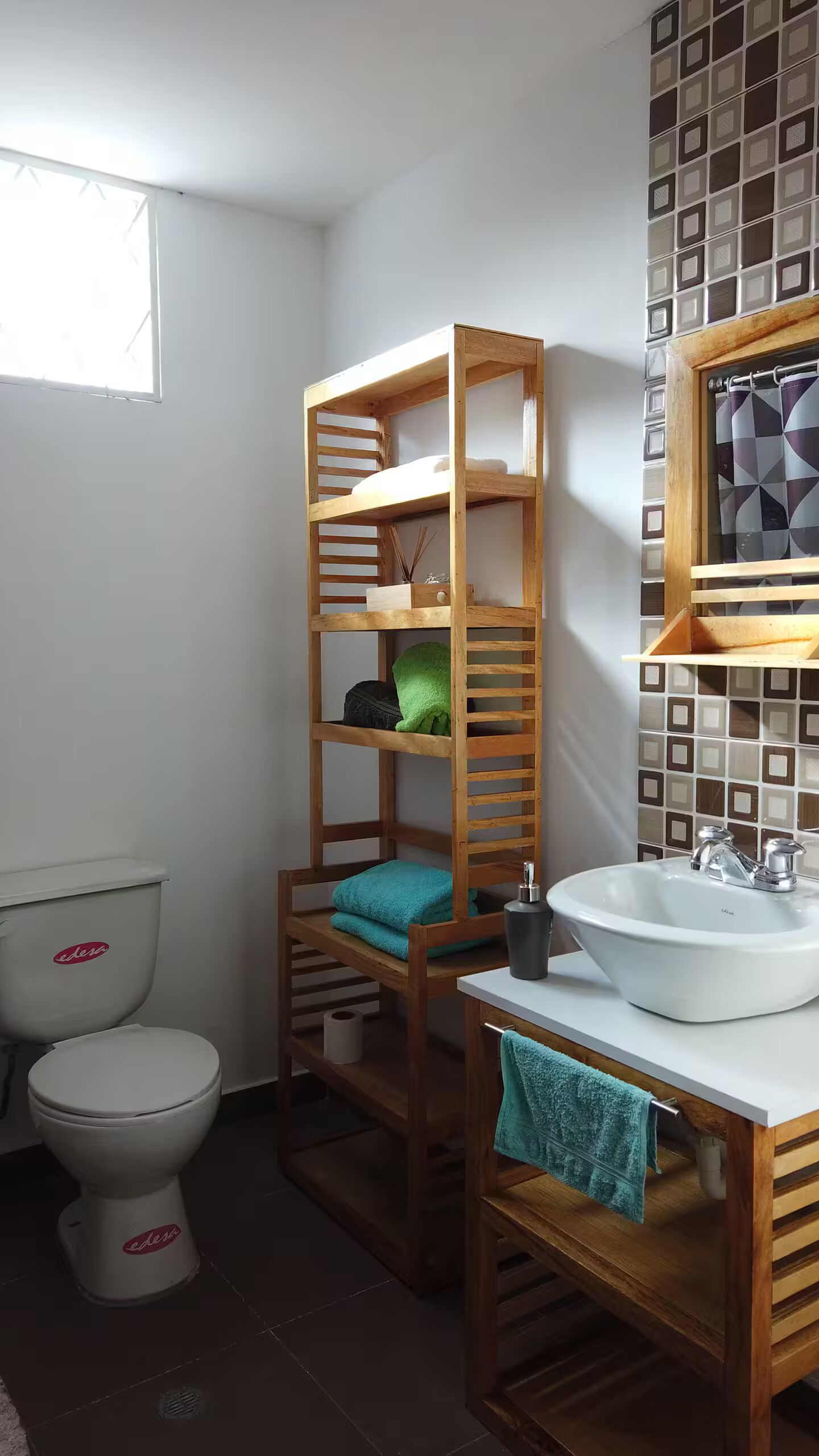 Une salle de bain avec une étagère en bois, des toilettes et un lavabo avec une serviette.