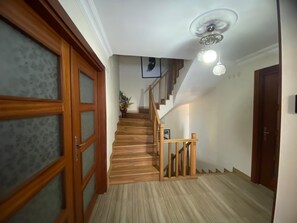 A wooden staircase with a handrail, a ceiling fan, and a wall-mounted light fixture.