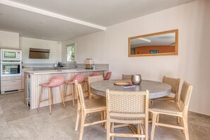 A modern kitchen with a central island, a dining area with wicker chairs, and a large mirror on the wall. - Luxury 3-bedroom apartment, 350 m from Saint-Clair beach (Le Lavandou)
