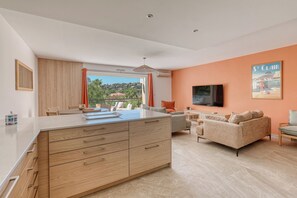A modern living room with a large island, sofa, and TV. - Luxury 3-bedroom apartment, 350 m from Saint-Clair beach (Le Lavandou)