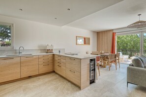 Eine moderne Küche mit Holzausstattung, einem Geschirrspüler und einem Essbereich mit Tisch und Stühlen.