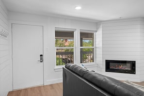 Ein modernes Wohnzimmer mit Kamin, einer Couch und einer Tür.