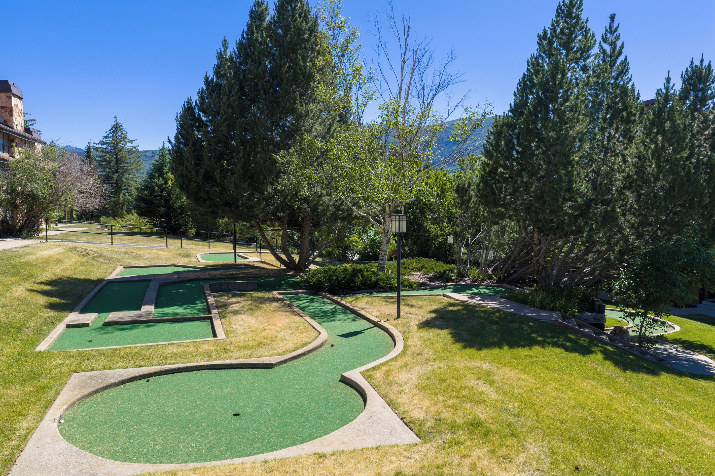 A golf course with multiple green areas and trees.