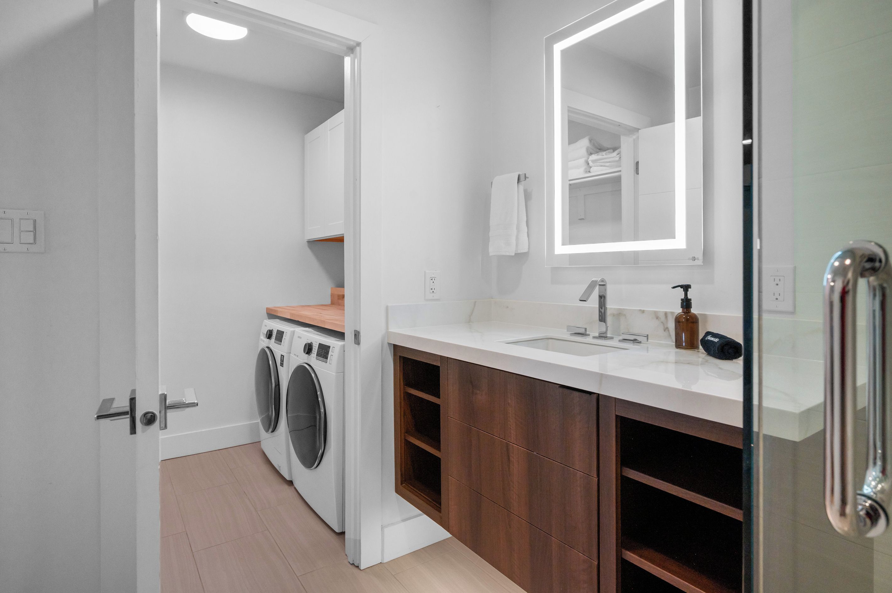Une petite salle de bain équipée d’un lave-linge, d’un évier, d’un miroir et de meubles en bois.