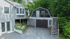 Uma casa de dois andares com garagem, varanda coberta e deck de madeira.