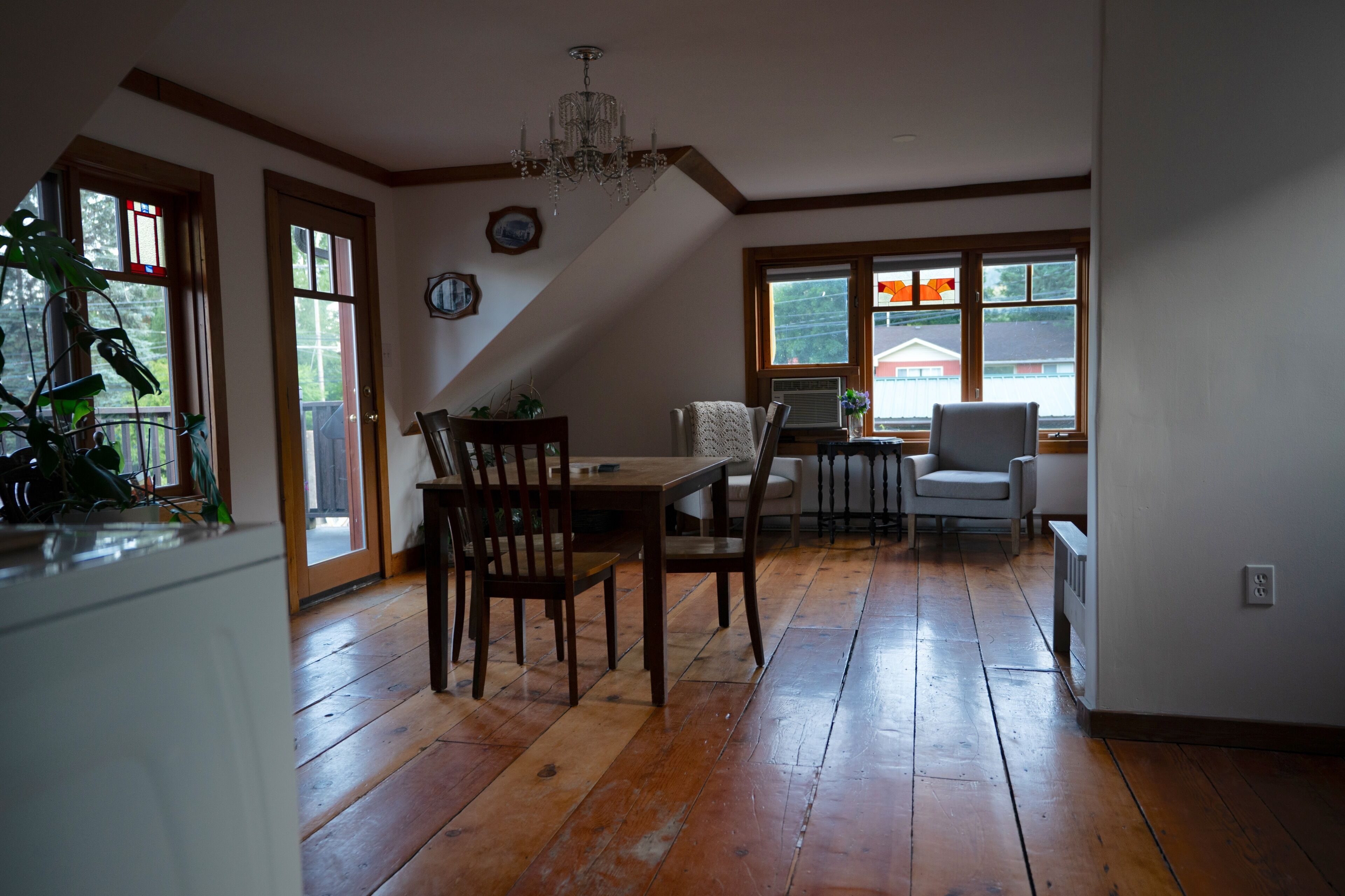A dining area with wooden flooring, a chandelier, and a view through large windows.