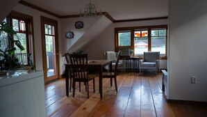 Ein Essbereich mit Holzboden, einem Kronleuchter und Blick durch große Fenster.