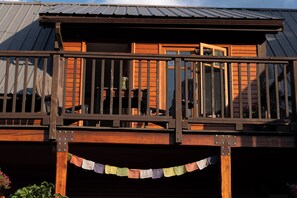 A wooden deck with a railing, a window, and a door. - Kaslo Manor Lodge - The Loki Suite  - perfect for groups/families, pet friendly (Kaslo)