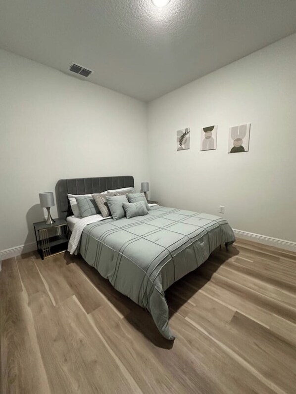 Een slaapkamer met een bed, nachtkastjes en wanddecoratie.