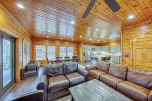 A log cabin interior with a wooden ceiling, leather sofas, a dining area, and a kitchen. - Newly Remodeled 4BR Suites Gatlinburg Cabin, Hot Tub & Theater Room (Gatlinburg)