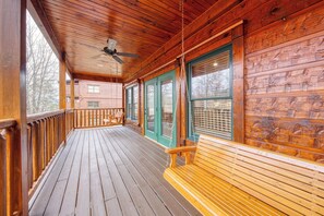 A wooden deck with a ceiling fan, wooden railings, and a bench. - Newly Remodeled 4BR Suites Gatlinburg Cabin, Hot Tub & Theater Room (Gatlinburg)