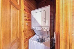 Ein kleiner Waschraum mit Holzvertäfelung, einer Waschmaschine und einem Trockner mit Frontlader.