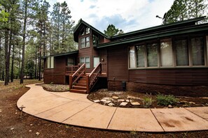 Eine zweistöckige Holzhütte mit überdachter Veranda und einem Kiesweg, der zum Eingang führt.