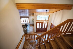 A wooden staircase leading to a living area with a sofa and a potted plant. - Primrose Pines Retreat located at the base of Mt Elden (Flagstaff)