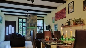 A dining area with a glass table, leather chairs, a chandelier, and artwork on the walls. - •Blood and Wisdom • Home - Art Gallery • Lodging, art, clay, and cardboard crafts• (San Cristóbal de las Casas)