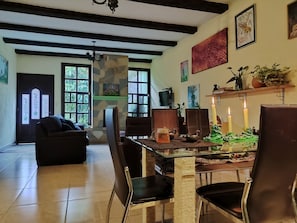 Ein Essbereich mit einem Glastisch, Ledersesseln, einer Chandelierleuchtre und Kunstwerken an den Wänden.