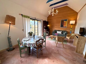 A cozy room with a dining table set for two, a sofa, a TV, and a chandelier. - Peskaour, An artist s house near the sea (Landéda)