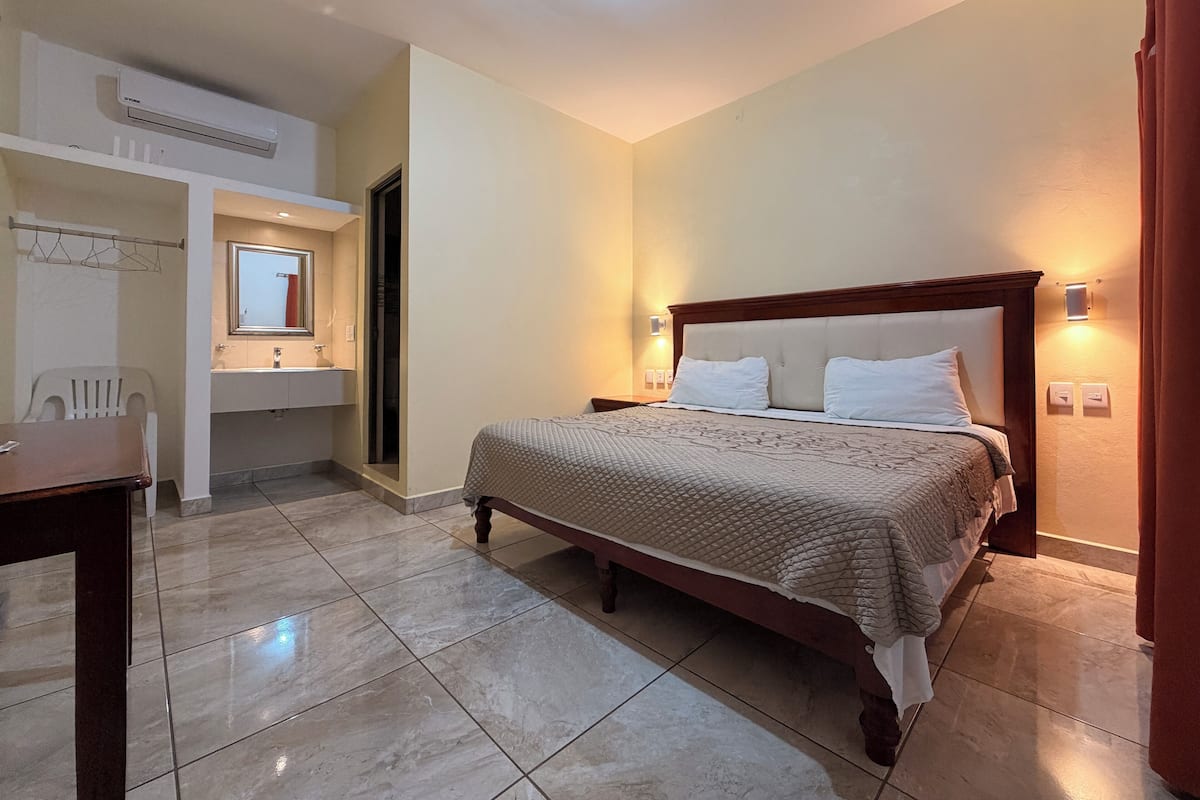 A hotel room with a bed, a bathroom, and a desk.