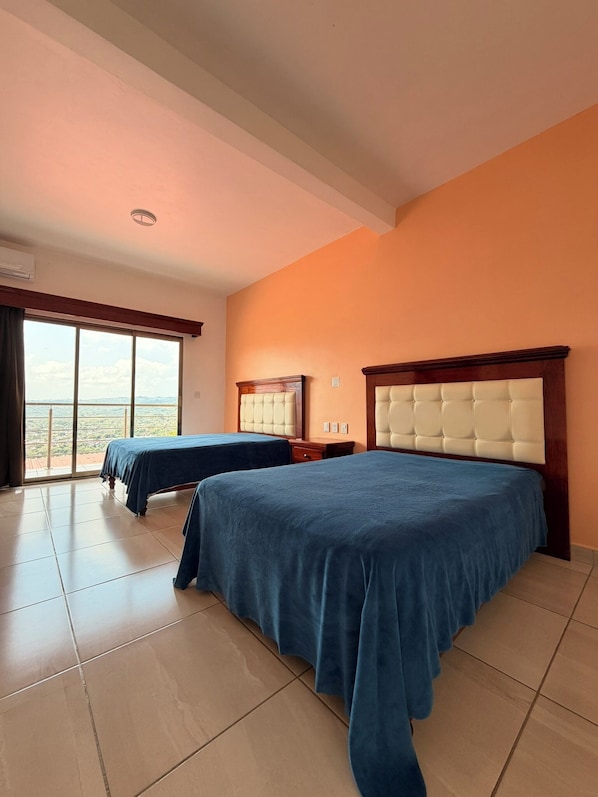 A hotel room with two beds, a large window, and a view of the landscape.