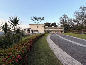 A multi-story building with a central courtyard, surrounded by manicured gardens and a paved driveway.