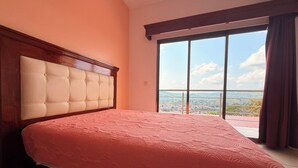 Un dormitorio con una cama grande, cabecera de madera y vistas a través de un ventanal corredero.