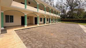Un edificio de varios pisos con un corredor cubierto y piso de piedra.