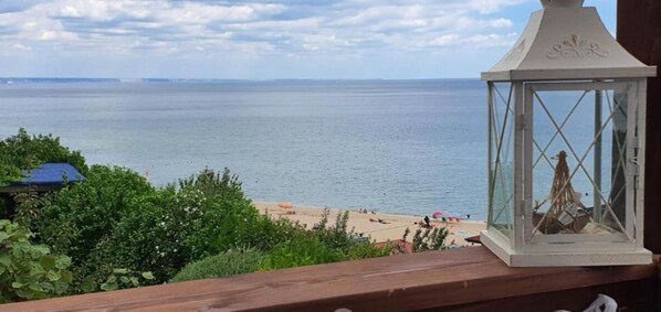 Vista de una playa con un farol blanco sobre una barandilla de madera.