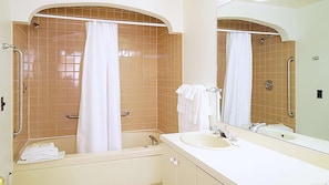 A bathroom with a bathtub, a shower, a sink, and a mirror.