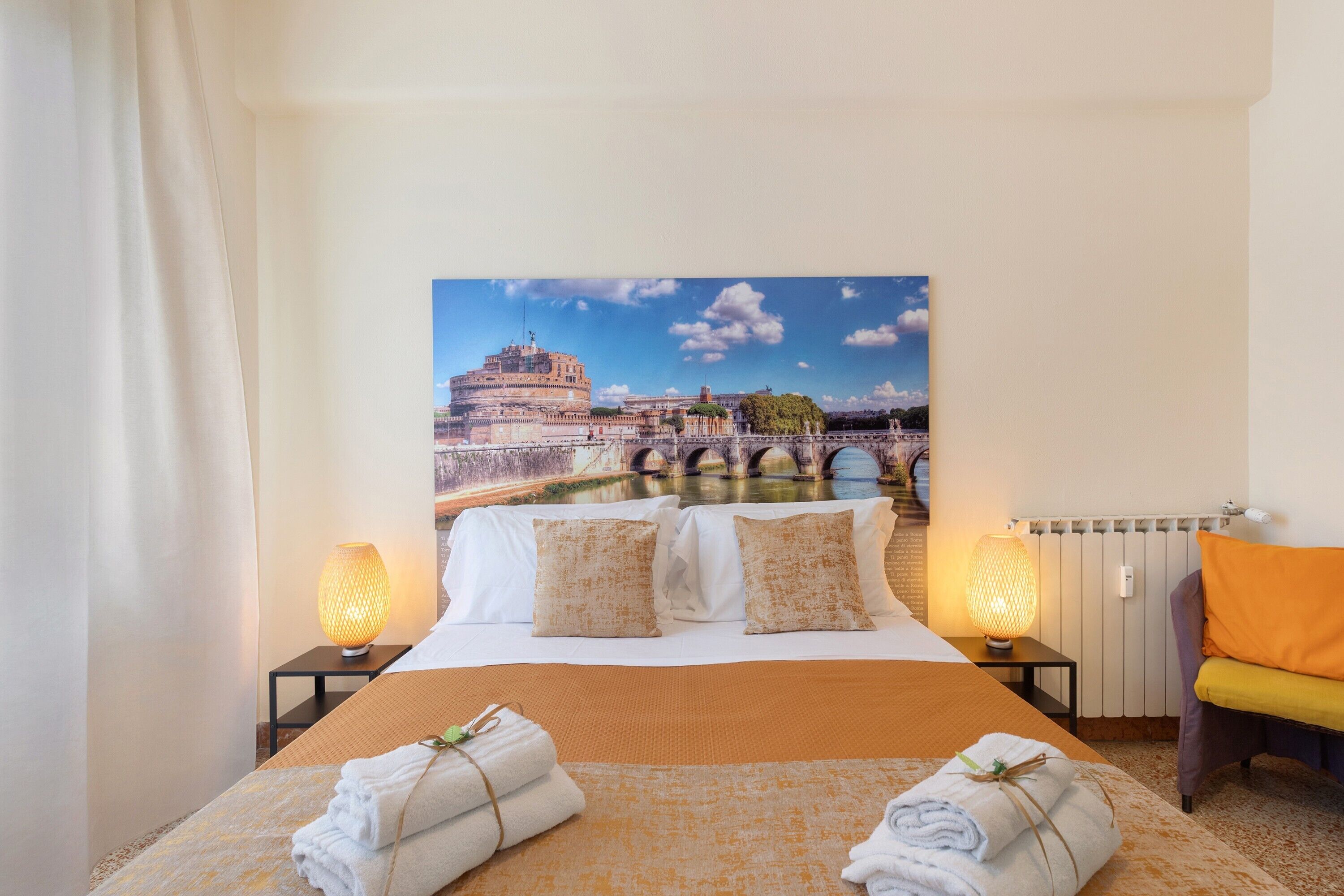A hotel room with a bed, two nightstands, a chair, and a large cityscape painting on the wall.
