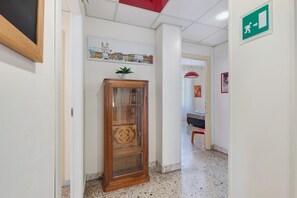 A hallway with a wooden cabinet, a cityscape artwork, and an emergency exit sign. - Apartment 'Il Sogno in Rome -' with Balcony, Wi-Fi and Air Conditioning (Rome)