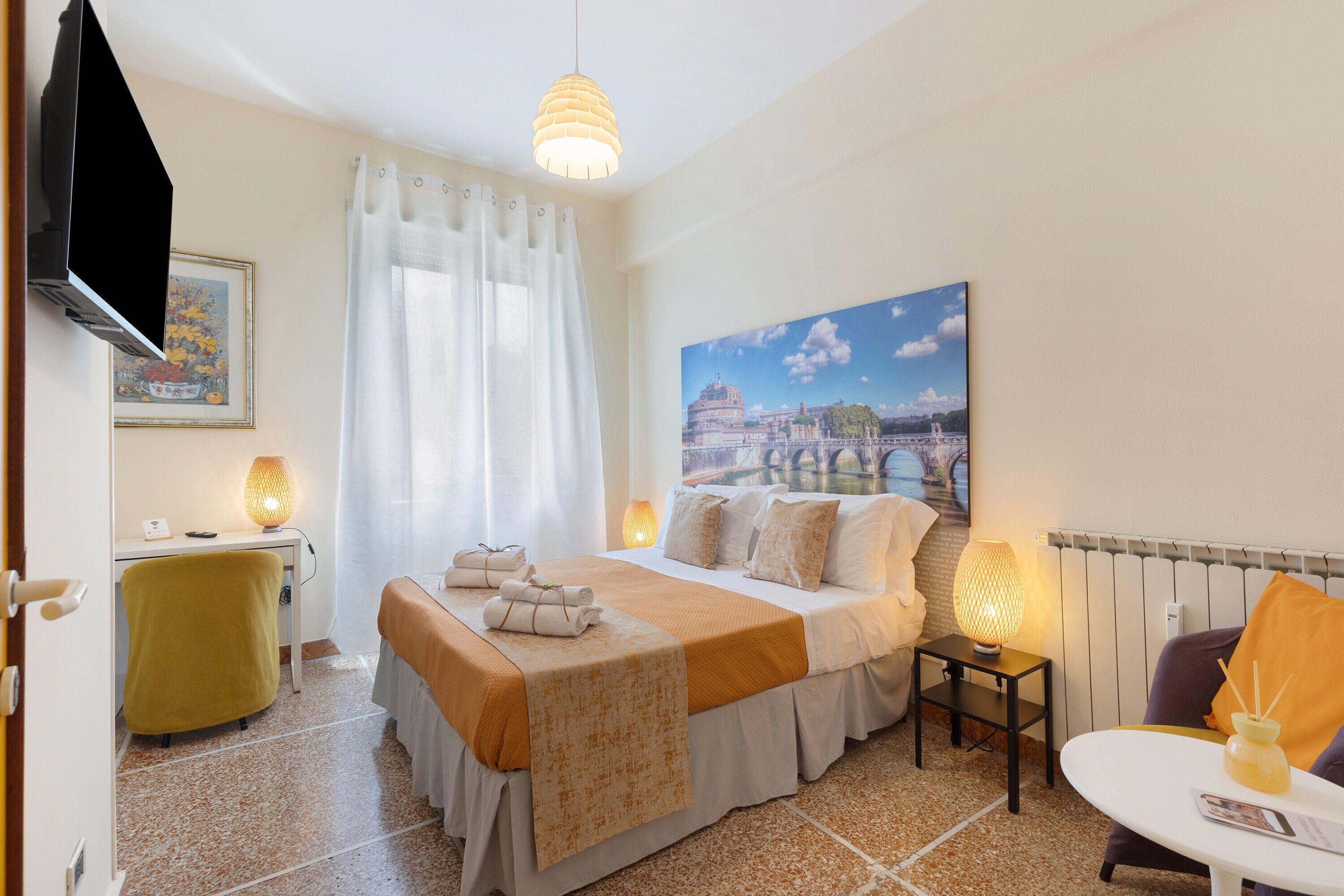 Une chambre d’hôtel avec un lit, un bureau, une chaise, une table et un tableau représentant un pont.