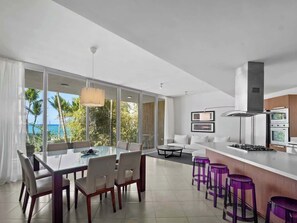 A modern kitchen with a large island, bar stools, and a view of the ocean. - Oceanfront Apartment w/ Beachfront Pool in (Cabarete)