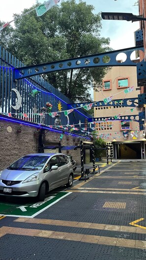 Une voiture était garée dans un espace de stationnement prévu à cet effet, délimité par une barrière métallique bleue et agrémenté de petits drapeaux décoratifs.