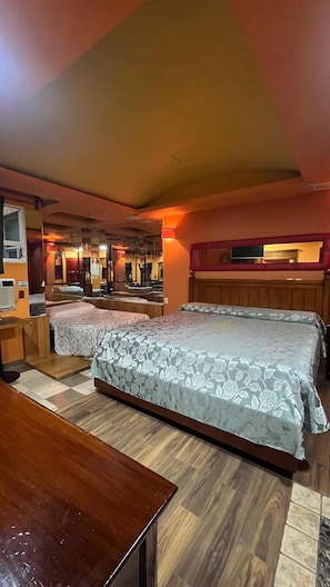 Habitación de hotel con dos camas, una mesa de madera, un espejo y una pared roja.