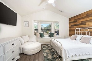Ein Schlafzimmer mit Bett, Fensterbank, Kommode und Fernseher.