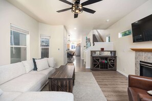 A spacious living area with a sofa, coffee table, fireplace, and a TV mounted on the wall. - Boise State Retreat | Walk to BSU & Downtown (Boise)