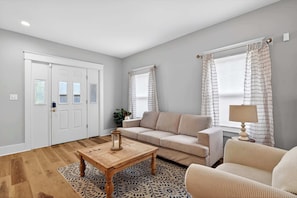 A living room with a sofa, a coffee table, and a lamp. - Grand Louisville estate near Historic Churchill! (Louisville)