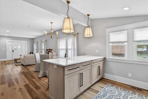 A modern kitchen with a central island, pendant lighting, and a view of the outdoors. - Grand Louisville estate near Historic Churchill! (Louisville)