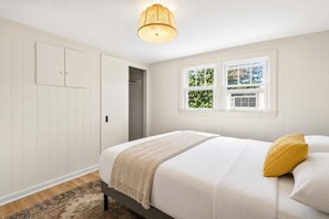 A bedroom with a bed, a window, a door, and a hanging light fixture. - Grand Louisville estate near Historic Churchill! (Louisville)
