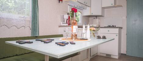 A compact kitchen with a dining table, a sofa, and a small window with lace curtains.