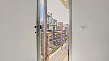 Uitzicht vanaf een balkon met een glazen deur, een metalen leuning en een kleine tafel met een stoel.