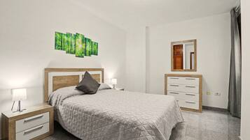 Un dormitorio con cama, mesitas de noche, cómoda, espejo y una obra de arte en la pared.