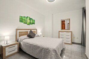 A bedroom with a bed, nightstands, a dresser, a mirror, and a wall art piece. - NG Candelaria – Comfortable Apartment with Terrace in Candelaria (Candelaria)
