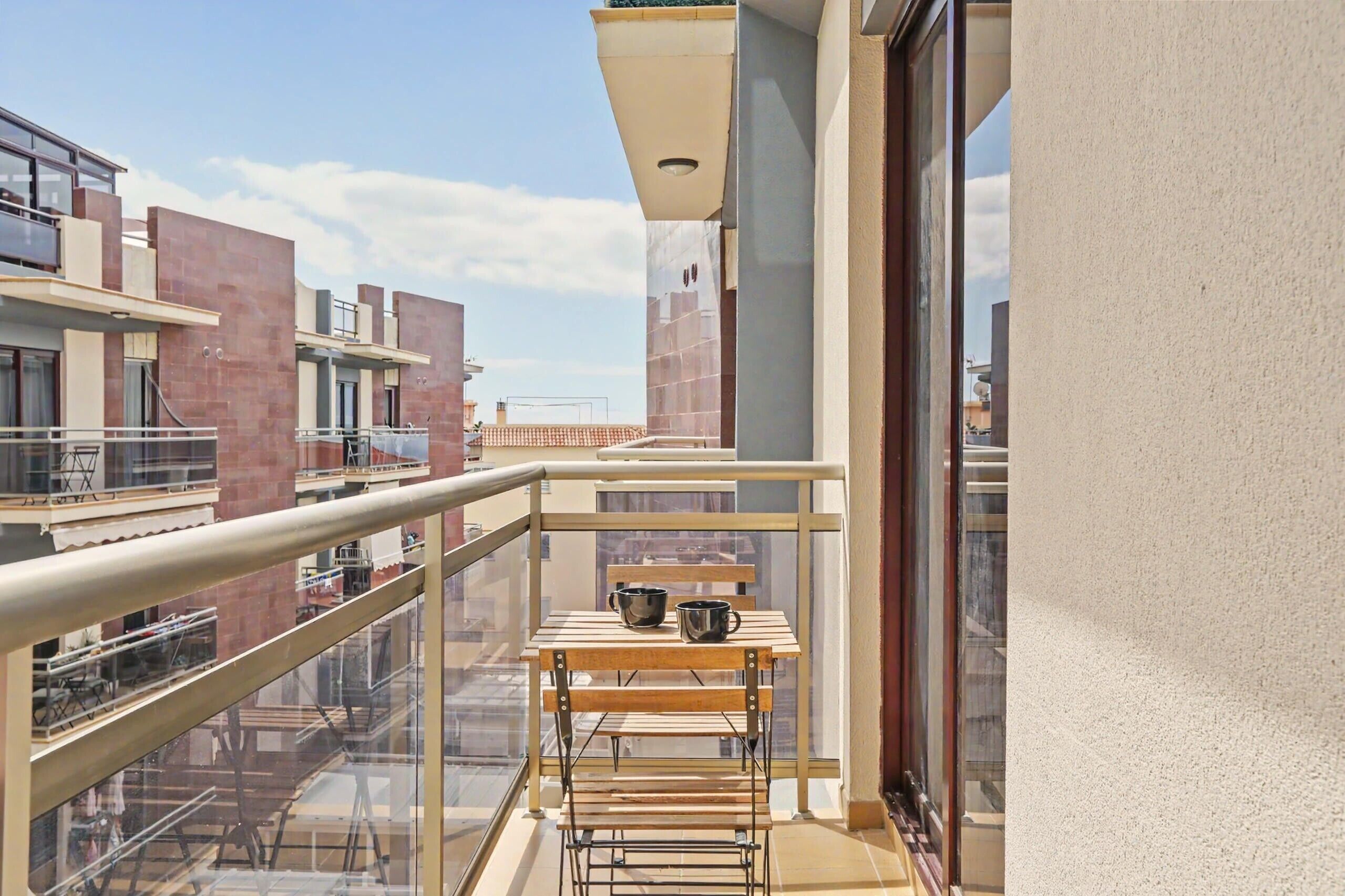 Un balcon avec une table, des chaises et un étendoir.