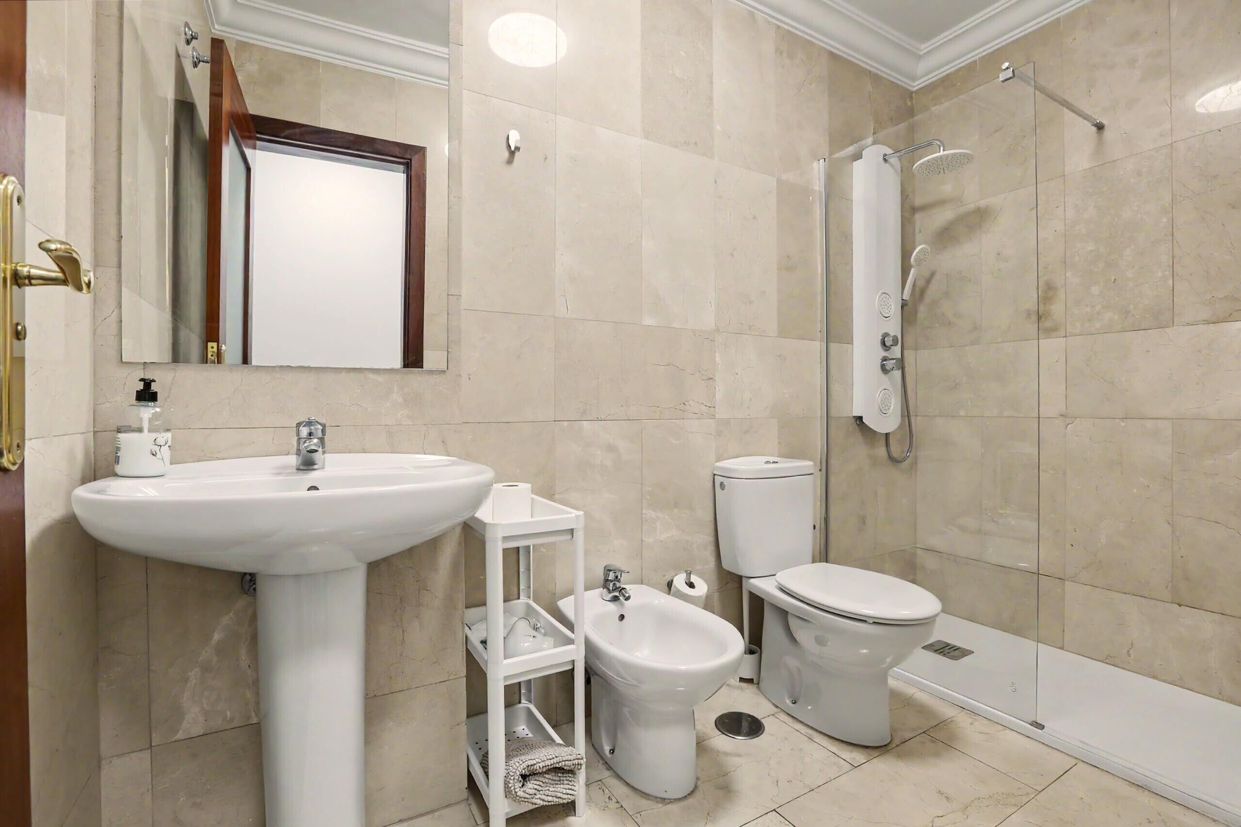 Un baño con lavamanos pedestal, bidé, inodoro y cabina de ducha.
