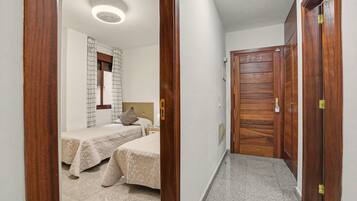 Een hotelkamer met twee bedden, een houten garderobe, een spiegel en een plafondlamp.