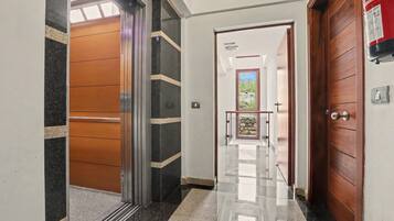 Un pasillo con piso pulido, una puerta de madera y vista a una habitación con ventana.