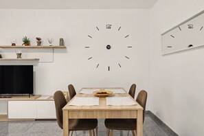 A dining area with a wooden table, four chairs, a central bowl, and two wall clocks. - NG Candelaria – Comfortable Apartment with Terrace in Candelaria (Candelaria)