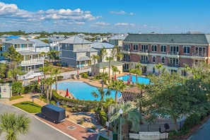 Zona residencial con piscina rodeada de casas y palmeras.