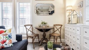 Um quarto com uma mesa de jantar, duas cadeiras, um sofá, um armário e uma placa com a inscrição 'BEACH HOUSE'.